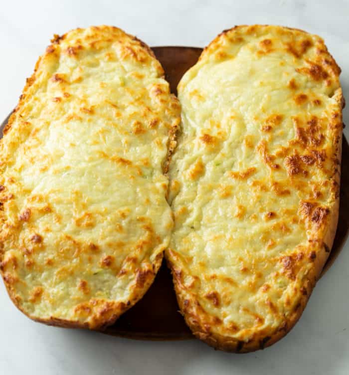 Pain français garni de beurre à l'ail et de fromage fondu avant de le trancher pour faire du pain à l'ail avec du fromage.